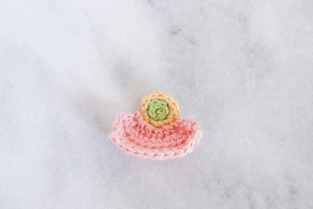pink crochet poppy flower petal on a marble background
