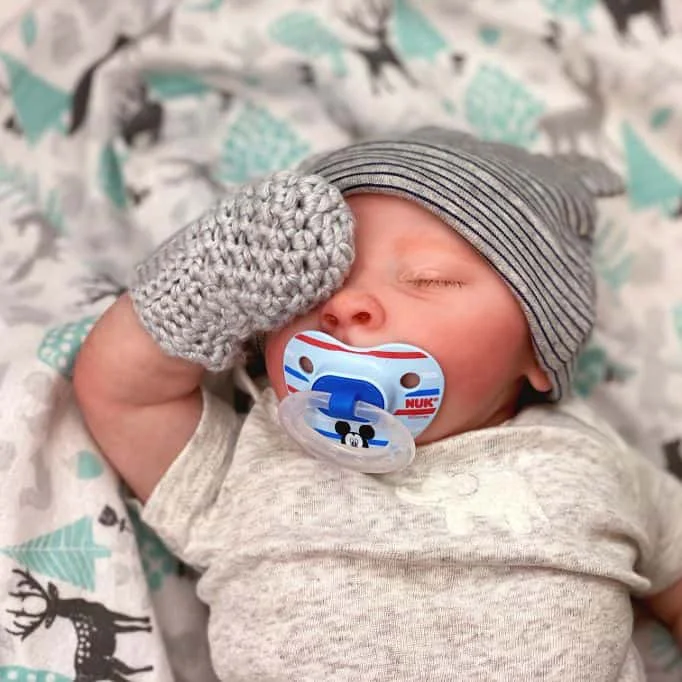 baby wearing a hat and pair of crochet baby mittens