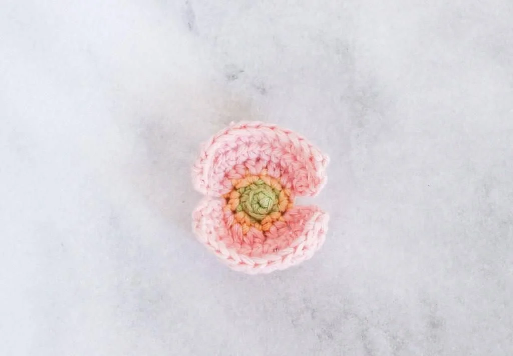 Pink crochet poppy flower with a green centre